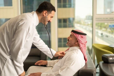  المتابعة الدورية لفحص نبضات القلب, طبيب عربي خليجي سعودي يرتدي المعطف الطبي يقوم باستخدام سماعه الفحص الطبية لمريض كبير بالسن, قياس  معدل ضربات القلب, مفهوم الطب والرعاية الصحية