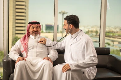  المتابعة الدورية لفحص نبضات القلب, طبيب عربي خليجي سعودي يرتدي المعطف الطبي يقوم باستخدام سماعه الفحص الطبية لمريض كبير بالسن, قياس  معدل ضربات القلب, مفهوم الطب والرعاية الصحية