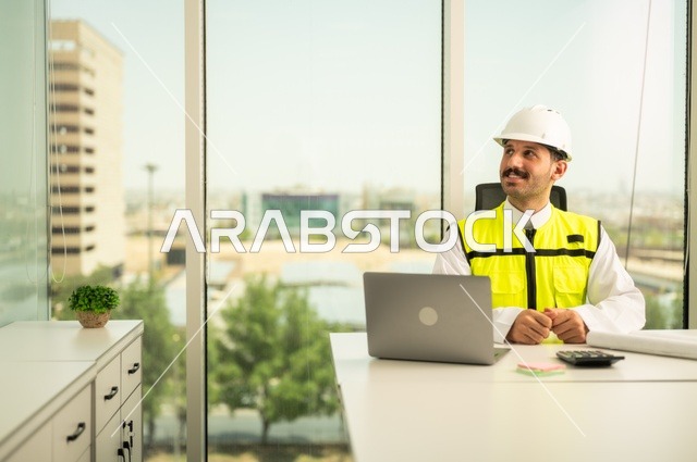 الاشراف على تطبيق المشاريع و الخطط الهندسيه المعمارية في البناء، دمج العمل مع التقنية و التكنولوجيا، الاطلاع على تصاميم هندسية جديدة على جهاز الحاسوب المحمول، مهندس معماري عربي سعودي خليجي يرتدي اللباس الخاص بالعمل