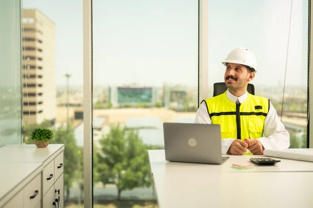 الاشراف على تطبيق المشاريع و الخطط الهندسيه المعمارية في البناء، دمج العمل مع التقنية و التكنولوجيا، الاطلاع على تصاميم هندسية جديدة على جهاز الحاسوب المحمول، مهندس معماري عربي سعودي خليجي يرتدي اللباس الخاص بالعمل