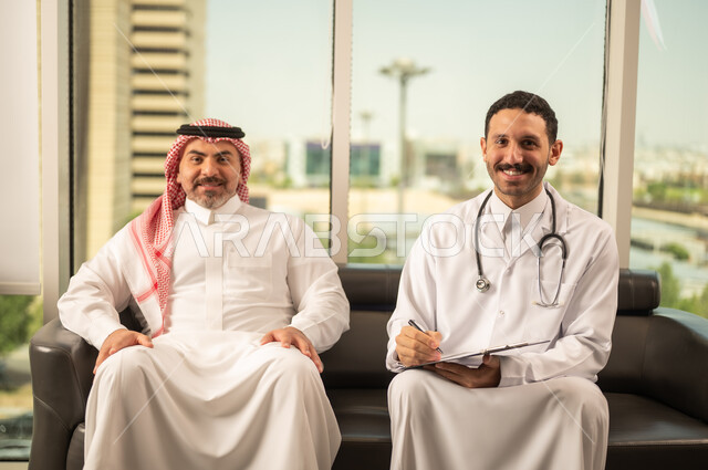 اعداد التقارير الطبية، تدوين نتائج الفحوصات بالسجل الطبي لمريض كبير بالسن، حسن التعامل مع المراجعين، ايماءات البشاشة والسرور، طبيب عربي خليجي سعودي يرتدي الثوب التقليدي والمعطف الابيض يحمل بيده ملفات المرضى، العمل في القطاع الصحي