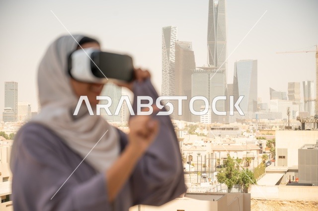 تقنيات حديثة الكترونية وأجهزة تكنولوجية، التفاعل ومحاكاة العالم الافتراضي الخيالي, صورة مقربة من الجانب لامرأة عربية خليجية سعودية محجبة تقف في المعرض تضع نظارات الفي ار, الاستمتاع في قضاء اوقات ترفيهية، قضاء وقت ممتع خارج المنزل
