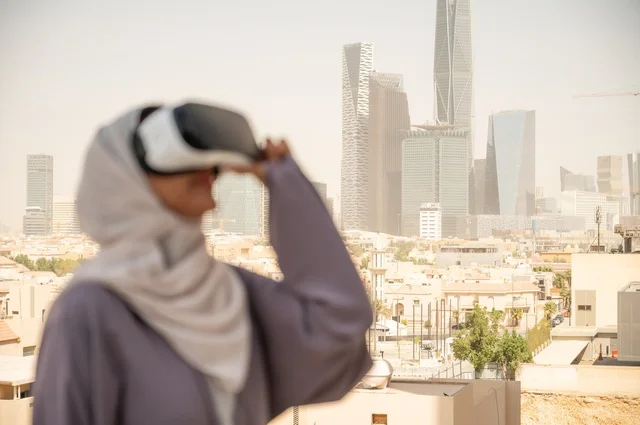 تقنيات حديثة الكترونية وأجهزة تكنولوجية، التفاعل ومحاكاة العالم الافتراضي الخيالي, صورة مقربة من الجانب لامرأة عربية خليجية سعودية محجبة تقف في المعرض تضع نظارات الفي ار, الاستمتاع في قضاء اوقات ترفيهية، قضاء وقت ممتع خارج المنزل