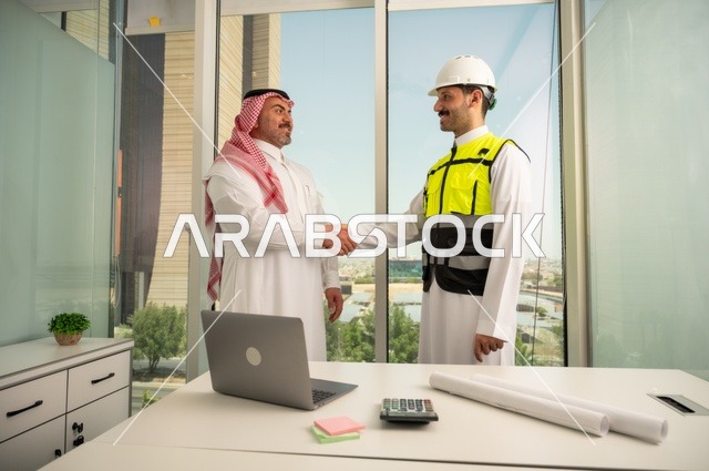 المصافحة والترحيب والاستقبال, مفهوم التعاون والعمل المشترك, مهندس عربي خليجي سعودي يرتدي الخوذة وسترة الحماية يقوم بمصافحة رجل اعمال يرتدي الشماغ و الثوب التقليدي، الاتفاق على الخطط والمشاريع الهندسية في موقع العمل , الإنشاءات المعمارية في الأراضي السعودية
