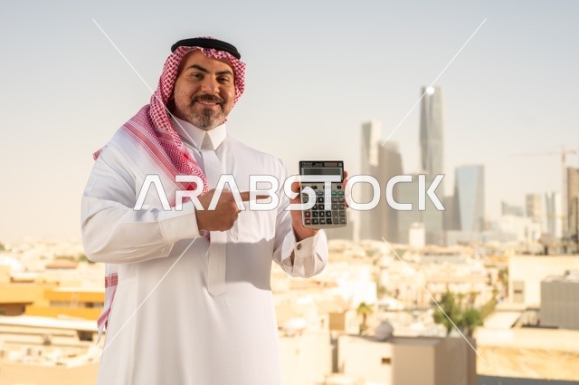 The concept of facilitating business and the ability to accomplish tasks, using modern technologies and advanced devices, a Saudi Arabian Gulf man wearing traditional clothing holding a calculator to perform calculations, a background of towers and skyscrapers in Riyadh