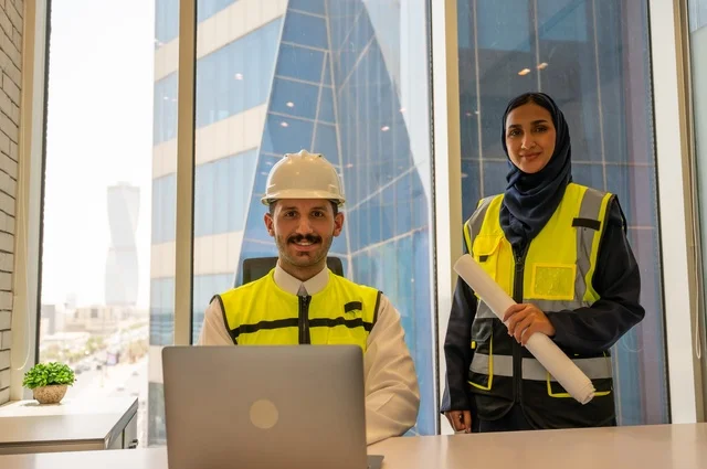 ادارة وانجاز المهام باستخدام جهاز تقني حديث ومتطور، مهنة ووظيفة مكتبية سعودية، مهندسان معماريان سعوديان خليجيان يحملان مخطط لمشروع البناء للتخطيط وتنفيذ العمل في داخل المكتب, إرتداء سترة الحماية الخاصة بالعمل, تدقيق العمل،  كتابة وتدوين البيانات والنتائج،