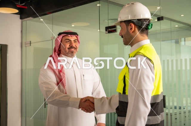 التفاهم والتعاون بين الزملاء، تبادل الخبرات والمعلومات لتحقيق الاهداف، مهندس عربي خليجي سعودي يرتدي سترة العمل وخوذة الحماية البيضاء يقف مع زميله، متابعة مخطط المشروع الهندسي وتدقيقه, مفهوم الهندسة والإنشاءات المعمارية، مشاريع إعمارية سعودية وطنية