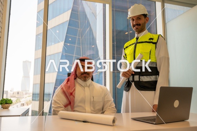 الاتفاق والشراكة على الأعمال والمشاريع، اجتماع في مكتب العمل، ايماءات السعادة والسرور،عقد صفقات عمل جديدة، تصوير من الجانب لرجل عربي خليجي سعودي يرتدي الثوب والشماغ مع زميله مهندس يرتدي الخوذة وسترة الحماية,  مشاريع إعمارية سعودية وطنية