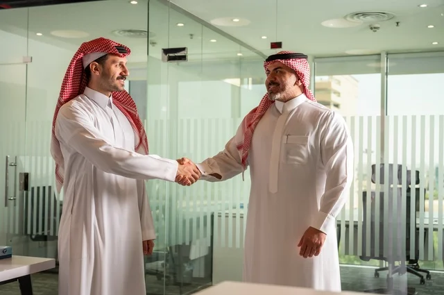 Friendships, acquaintance, and building social relationships, successful new business deals between businessmen, two Saudi Arabian Gulf men in traditional attire shaking hands, expanding fields of work, partnership in business and engineering projects.