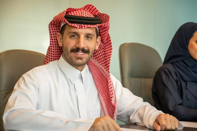 إدارة شؤون الأعمال وتنظيمها، مهنة ووظيفة ادارية مكتبية، رجل عربي خليجي سعودي ينظر إلى الكاميرا بإيماءات سروروسعادة يرتدي الثوب التقليدي داخل قاعة الاجتماع، الشركات والمكاتب في المملكة العربية السعودية