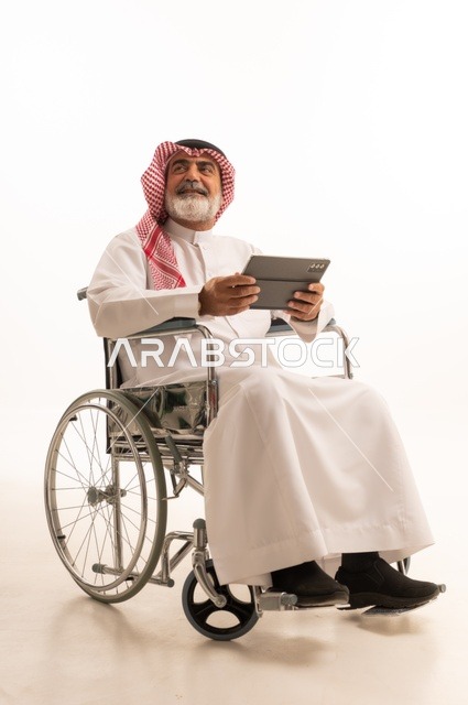 الاستفادة من التقنيات الحديثة والتكنولوجيا المتطورة، تأمين اجهزة ومعدات تساعد بالحركة والتنقل، ضعف القدرة الحركية، بورتريه لرجل عربي خليجي سعودي من ذوي الاحتياجات الخاصة يرتدي الثوب التقليدي والشماغ يجلس على كرسي متحرك ويحمل بيده الجهاز اللوحي، خلفية بيضاء