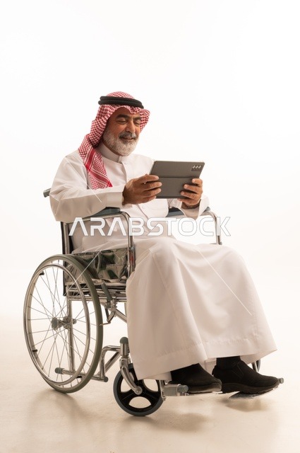 Utilizing modern techniques and advanced technology, providing devices and equipment that assist with movement and mobility, impaired motor ability, portrait of a Saudi Arabian Gulf man with special needs wearing traditional thobe and shemagh sitting in a wheelchair and holding a tablet in his hand, white background