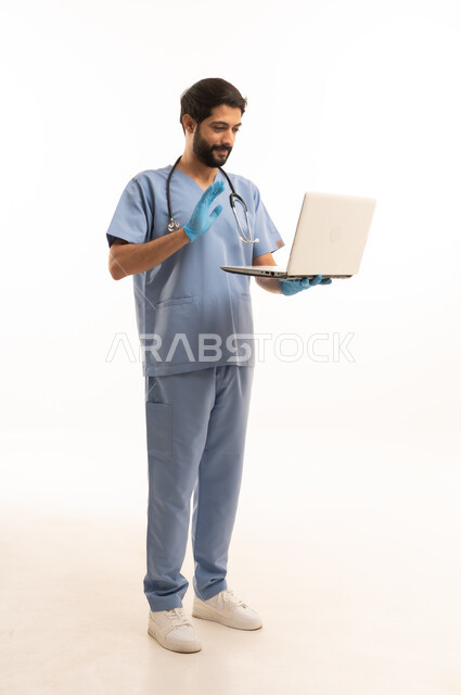 دمح التكنولوجيا في المجال الطبي، مفهوم الطب والرعاية الصحية، بورتريه لممرص عربي خليجي سعودي يرتدي اليونيفورم مع السماعة الطبية يقدم الخدمات للمرضى ويحمل بيده الحاسوب المحمول، مهنة ووظيفة طبية، العمل في القطاع الصحي في المملكة، الجسم بالطول الكامل، خلفيه بيضاء