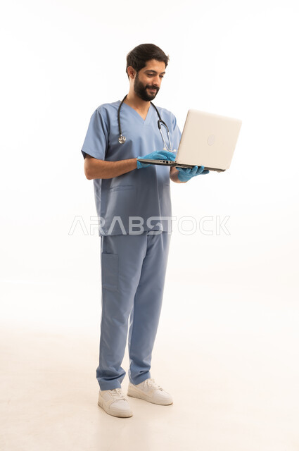 دمح التكنولوجيا في المجال الطبي، مفهوم الطب والرعاية الصحية، بورتريه لممرص عربي خليجي سعودي يرتدي اليونيفورم مع السماعة الطبية يقدم الخدمات للمرضى ويحمل بيده الحاسوب المحمول، مهنة ووظيفة طبية، العمل في القطاع الصحي في المملكة، الجسم بالطول الكامل، خلفيه بيضاء
