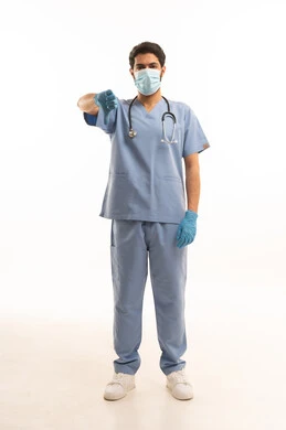 مفهوم التقييم السلبي، الطب والرعاية الصحية، بورتريه لممرص عربي خليجي سعودي يرتدي اليونيفورم مع السماعة الطبية يقدم الخدمات الصحية للمرضى ويشير باصبع الابهام للاسفل، مهنة ووظيفة طبية، العمل في القطاع الصحي في المملكة، الجسم بالطول الكامل، خلفيه بيضاء