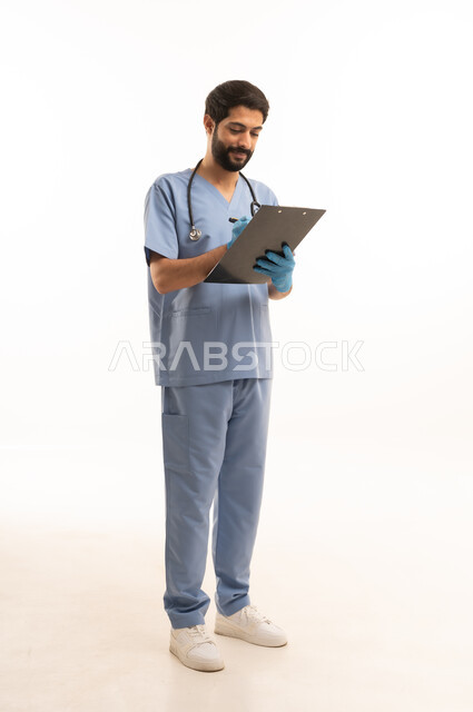 تسجيل وتدوين المعلومات، مفهوم الطب والرعاية الصحية، بورتريه لممرض عربي خليجي سعودي يرتدي اليونيفورم مع السماعة الطبية يقدم الخدمات الصحية للمرضى في المراكز والمستشفيات، مهنة ووظيفة طبية، العمل في القطاع الصحي في المملكة، الجسم بالطول الكامل، خلفيه بيضاء