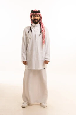 مفهوم الطب والرعاية الصحية، بورتريه لطبيب عربي خليجي سعودي يرتدي الثوب التقليدي مع المعطف والسماعة الطبية يقدم الخدمات الصحية للمرضى في المراكز والمستشفيات، مهنة ووظيفة طبية، العمل في القطاع الصحي في المملكة، الجسم بالطول الكامل، خلفيه بيضاء