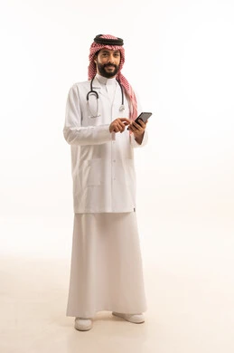 مهنة ووظيفة طبية، مفهوم الطب والرعاية الصحية، بورتريه لطبيب عربي خليجي سعودي يرتدي الثوب التقليدي مع المعطف والسماعة الطبية يحمل بيده الهاتف المحمول، تقديم الخدمات الصحية للمرضى، العمل في القطاع الصحي في المملكة، الجسم بالطول الكامل، خلفيه بيضاء