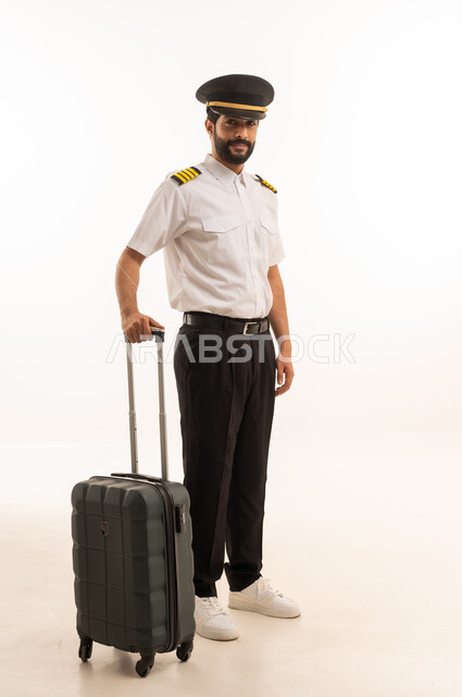 Blank black screen view on mobile phone, tourism and travel concept, welcome and reception crew, aviation work, tourist flights, Saudi Airlines, portrait of smiling Saudi Arabian Gulf Arab pilot in uniform pulling suitcase, full body, white background