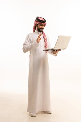 إدارة شؤون الأعمال وتنظيمها عبر الاجهزة التقنية، مهنة ووظيفة ادارية، دمج العمل مع التكنولوجيا، بورتريه لرجل عربي خليجي سعودي يرتدي الثوب التقليدي والشماغ يعمل على الحاسوب المحمول، استخدام جهاز تقني حديث ومتطور، العمل عن بعد وانجاز المهام المطلوبة، خلفية بيضاء 