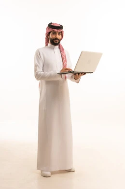 إدارة شؤون الأعمال وتنظيمها عبر الاجهزة التقنية، مهنة ووظيفة ادارية، دمج العمل مع التكنولوجيا، بورتريه لرجل عربي خليجي سعودي يرتدي الثوب التقليدي والشماغ يعمل على الحاسوب المحمول، استخدام جهاز تقني حديث ومتطور، العمل عن بعد وانجاز المهام المطلوبة، خلفية بيضاء 