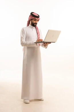 إدارة شؤون الأعمال وتنظيمها عبر الاجهزة التقنية، مهنة ووظيفة ادارية، دمج العمل مع التكنولوجيا، بورتريه لرجل عربي خليجي سعودي يرتدي الثوب التقليدي والشماغ يعمل على الحاسوب المحمول، استخدام جهاز تقني حديث ومتطور، العمل عن بعد وانجاز المهام المطلوبة، خلفية بيضاء 