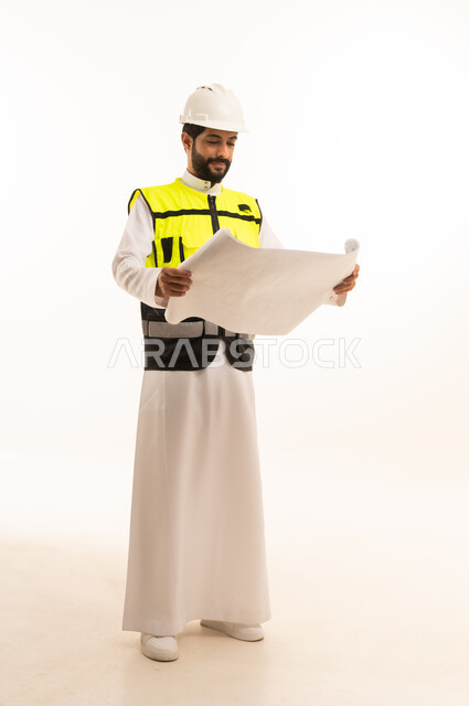 مشاريع إعمارية سعودية وطنية، مفهوم الهندسة المعمارية، متابعة مخطط المشروع الهندسي وتدقيقه, الاهتمام بالتطور العمراني بسواعد المهندسين السعوديين, بورتريه لمهندس عربي خليجي سعودي يرتدي سترة العمل وخوذة الحماية يحمل بيده المخطط، الجسم بالطول الكامل، خلفية بيضاء