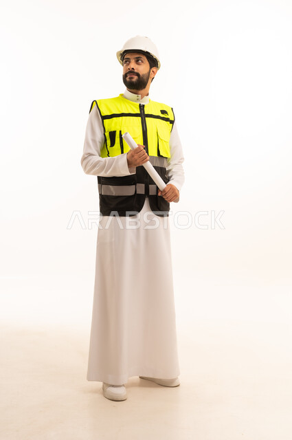 مشاريع إعمارية سعودية وطنية، مفهوم الهندسة المعمارية، متابعة مخطط المشروع الهندسي وتدقيقه, الاهتمام بالتطور العمراني بسواعد المهندسين السعوديين, بورتريه لمهندس عربي خليجي سعودي يرتدي سترة العمل وخوذة الحماية يحمل بيده المخطط، الجسم بالطول الكامل، خلفية بيضاء