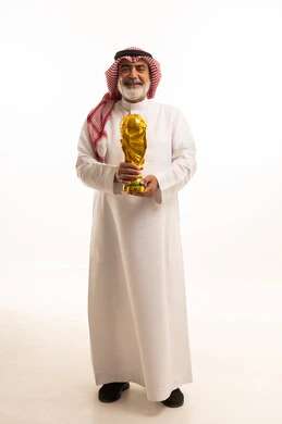Expressions of joy, happiness and enthusiasm for competition, concept of winning and winning, cheering for the Saudi team, winning the championship and obtaining first place, portrait of a Saudi Arabian Gulf man wearing traditional thobe and shemagh holding a golden football cup in his hand, full body image, white background