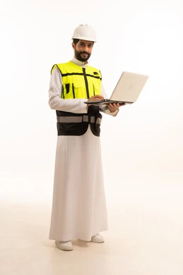 استخدام جهاز تقني حديث ومتطور، مشاريع إعمارية سعودية وطنية، مفهوم الهندسة المعمارية، الاهتمام بالتطور العمراني بسواعد المهندسين السعوديين, بورتريه لمهندس عربي خليجي سعودي يرتدي سترة العمل وخوذة الحماية يحمل بيده الحاسوب المحمول، الجسم بالطول الكامل، خلفية بيضاء