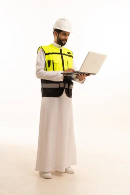 استخدام جهاز تقني حديث ومتطور، مشاريع إعمارية سعودية وطنية، مفهوم الهندسة المعمارية، الاهتمام بالتطور العمراني بسواعد المهندسين السعوديين, بورتريه لمهندس عربي خليجي سعودي يرتدي سترة العمل وخوذة الحماية يحمل بيده الحاسوب المحمول، الجسم بالطول الكامل، خلفية بيضاء