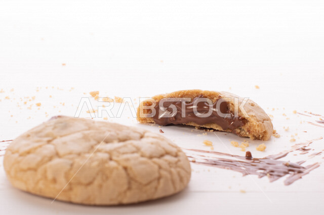 Picture of pieces of crispy biscuits scattered on a white background, pieces of biscuits stuffed with chocolate chips.