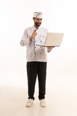 مشاهدة وصفات الطبخ الالكترونية, احتراف مهنة طهي الطعام السعودي, بورتريه لشيف عربي خليجي سعودي يرتدي يونيفورم الطبخ يمسك بيده الحاسوب المحمول، الجسم بالطول الكامل, خلفية بيضاء