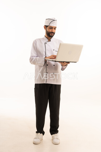 Watch online cooking recipes, professional Saudi cooking profession, portrait of a Saudi Arabian Gulf chef wearing a cooking uniform holding a laptop in his hand, full body, white background
