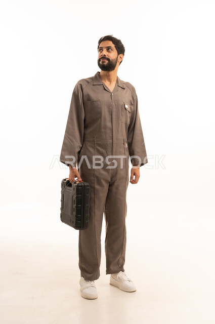 Skill and mastery of work, using maintenance equipment to make repairs, portrait of a Saudi Arabian Gulf man wearing a work uniform holding a tool bag, full body, white background
