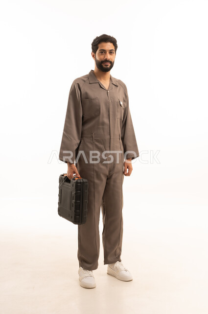 Skill and mastery of work, using maintenance equipment to make repairs, portrait of a Saudi Arabian Gulf man wearing a work uniform holding a tool bag, full body, white background