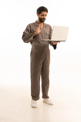 استخدام جهاز تقني حديث, المهارة و اتقان العمل، استعمال معدات الصيانة لاجراء التصليحات، بورتريه لرجل عربي سعودي خليجي يرتدي يونيفورم العمل يحمل الحاسب المحمول, الجسم بالطول الكامل، خلفية بيضاء