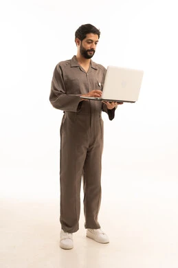 استخدام جهاز تقني حديث, المهارة و اتقان العمل، استعمال معدات الصيانة لاجراء التصليحات، بورتريه لرجل عربي سعودي خليجي يرتدي يونيفورم العمل يحمل الحاسب المحمول, الجسم بالطول الكامل، خلفية بيضاء