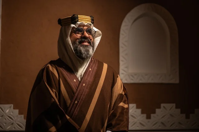 الحنين والأصالة  للأيام القديمة، رجل عربي سعودي مسن ينظر إلى الكاميرا بإيماءات الوقار والسرور يرتدي الزي العربي التقليدي يقف داخل غرفة تراثية بديكورات جدران مزخرفة، يرتدي عباءة واسعة وعقالًا على رأسه، ويبدو بلحية بيضاء، الحكمة والتجربة الطويلة في الحياة،