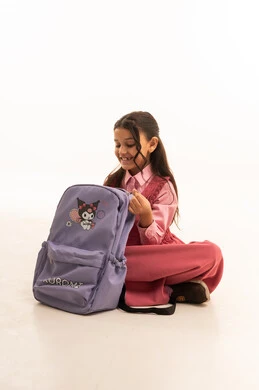 Preparing for the new school year, expressions and gestures of happiness and pleasure, portrait of a smiling Saudi Arabian Gulf girl wearing a school uniform packing her school bag, getting ready to go to the first day of school, love of learning and education, white background