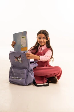 Preparing for the first day of school, love of learning and education, preparing for the new school year, expressions and gestures of happiness and pleasure, portrait of a smiling Saudi Arabian Gulf girl wearing a school uniform packing her school bag, white background