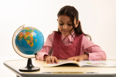 The importance of education in building a bright future for society, the concept of research and exploration around the world, a portrait of a Saudi Arabian Gulf student wearing a school uniform sitting at an office table studying school lessons, white background