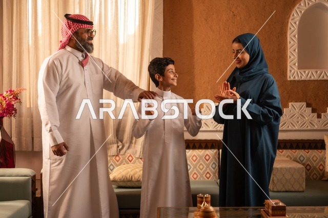 ألعاب الأصابع تضيف جوا من المتعة والتسلية، إظهار مشاعر المودة والمحبة العائلية, عائلة عربية خليجية سعودية تقف داخل غرفة تراثية بديكورات جدران عصرية، تفاصيل المكان المزخرف مع لمسات ديكور تراثية عربية ومزهرية تحتوي على ورود ملونة، التسلية في وقت الفراغ