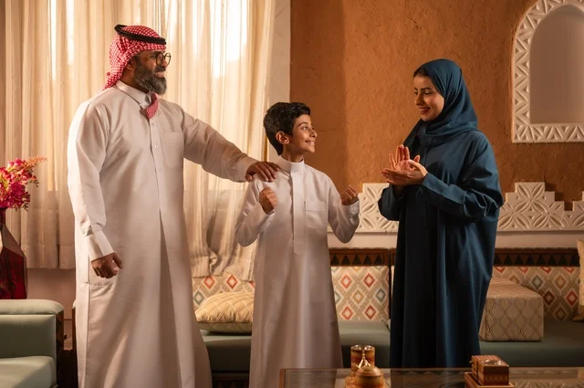 ألعاب الأصابع تضيف جوا من المتعة والتسلية، إظهار مشاعر المودة والمحبة العائلية, عائلة عربية خليجية سعودية تقف داخل غرفة تراثية بديكورات جدران عصرية، تفاصيل المكان المزخرف مع لمسات ديكور تراثية عربية ومزهرية تحتوي على ورود ملونة، التسلية في وقت الفراغ