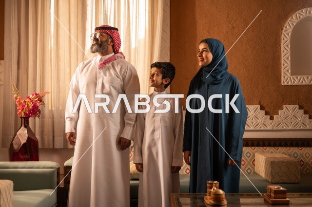 Contemplation of an outdoor scene, showcasing feelings of affection and family love, a Saudi Gulf Arab family standing inside a traditional room with decorated walls, details of the ornate place with touches of traditional Arab decor and a vase containing colorful flowers, leisure in free time.