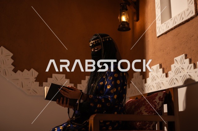 شغف مطالعة الكتب، إظهار مشاعر حب الوطن والانتماء إليه, الفخر بالهوية الوطنية, إمرأة عربية خليجية سعودية ترتدي العباءة السوداء والبرقع تقوم بقراءة كتاب في بيت تراثي قديم, يوم بدينا 1727 م, ذكرى تأسيس الدولة السعودية الأولى في 22 فبراير، ارتداء الأزياء الشعبية التقليدي