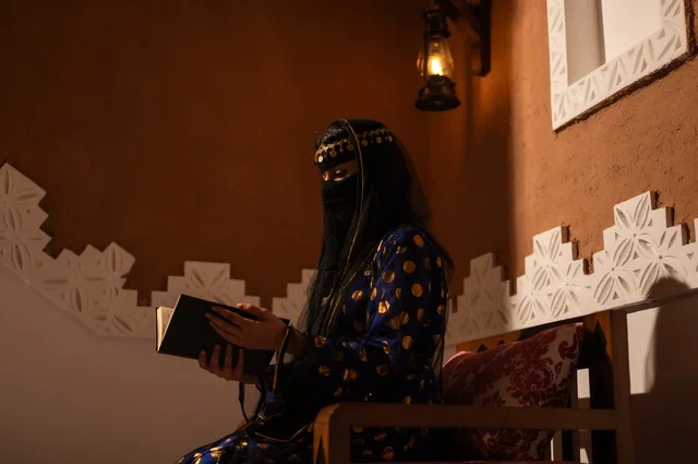 شغف مطالعة الكتب، إظهار مشاعر حب الوطن والانتماء إليه, الفخر بالهوية الوطنية, إمرأة عربية خليجية سعودية ترتدي العباءة السوداء والبرقع تقوم بقراءة كتاب في بيت تراثي قديم, يوم بدينا 1727 م, ذكرى تأسيس الدولة السعودية الأولى في 22 فبراير، ارتداء الأزياء الشعبية التقليدي