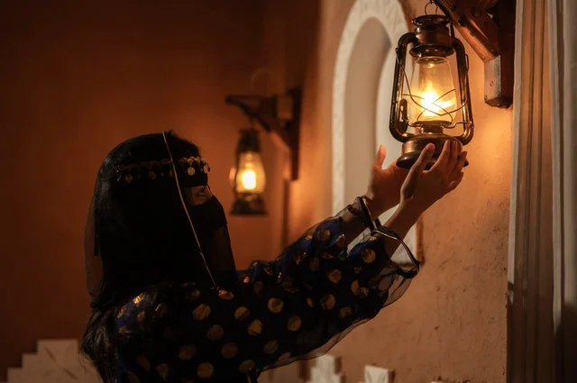 إظهار مشاعر حب الوطن والانتماء إليه, الفخر بالهوية الوطنية, إمرأة عربية خليجية سعودية ترتدي العباءة السوداء والبرقع تمسك بيدها فانوس معدني في بيت تراثي قديم, يوم بدينا 1727 م, ذكرى تأسيس الدولة السعودية الأولى في 22 فبراير، ارتداء الأزياء الشعبية التقليدي