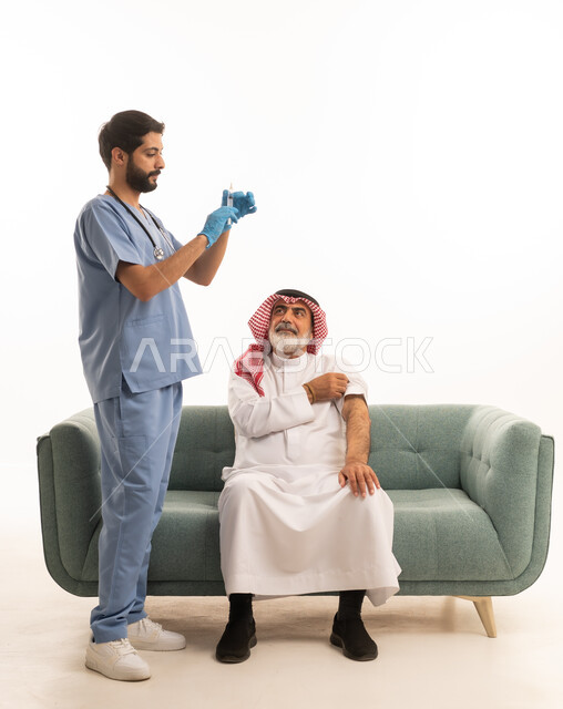 الاستعداد لأخذ الحقنة المسكنة للألم، مفهوم العمل في شركات التمريض المنزلي، تقديم أفضل الخدمات الطبية المنزلية للمرضى كبار السن، بورتريه لممرض يرتدي اللباس الطبي يقوم بإعطاء ابرة لرجل كبير بالسن عربي خليجي سعودي يرتدي الشماغ والثوب ويجلس على كنبه، خلفية بيضاء