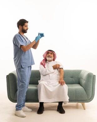 الاستعداد لأخذ الحقنة المسكنة للألم، مفهوم العمل في شركات التمريض المنزلي، تقديم أفضل الخدمات الطبية المنزلية للمرضى كبار السن، بورتريه لممرض يرتدي اللباس الطبي يقوم بإعطاء ابرة لرجل كبير بالسن عربي خليجي سعودي يرتدي الشماغ والثوب ويجلس على كنبه، خلفية بيضاء